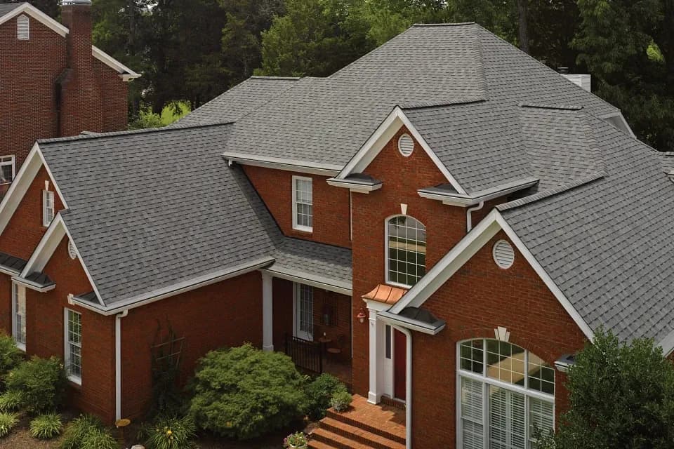 Gray architectural shingle roof across multiple gables and dormers on a brick home